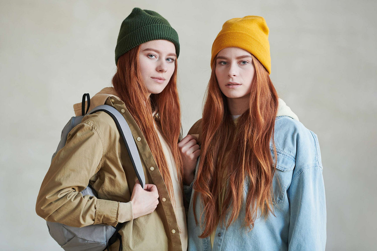 Zwei junge Frauen mit Mützen und Rucksack