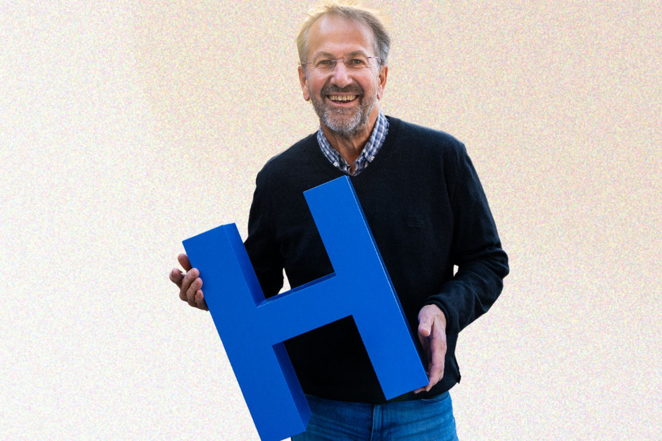 Mann hält blauen Buchstaben H in der Hand. H steht für Heimat