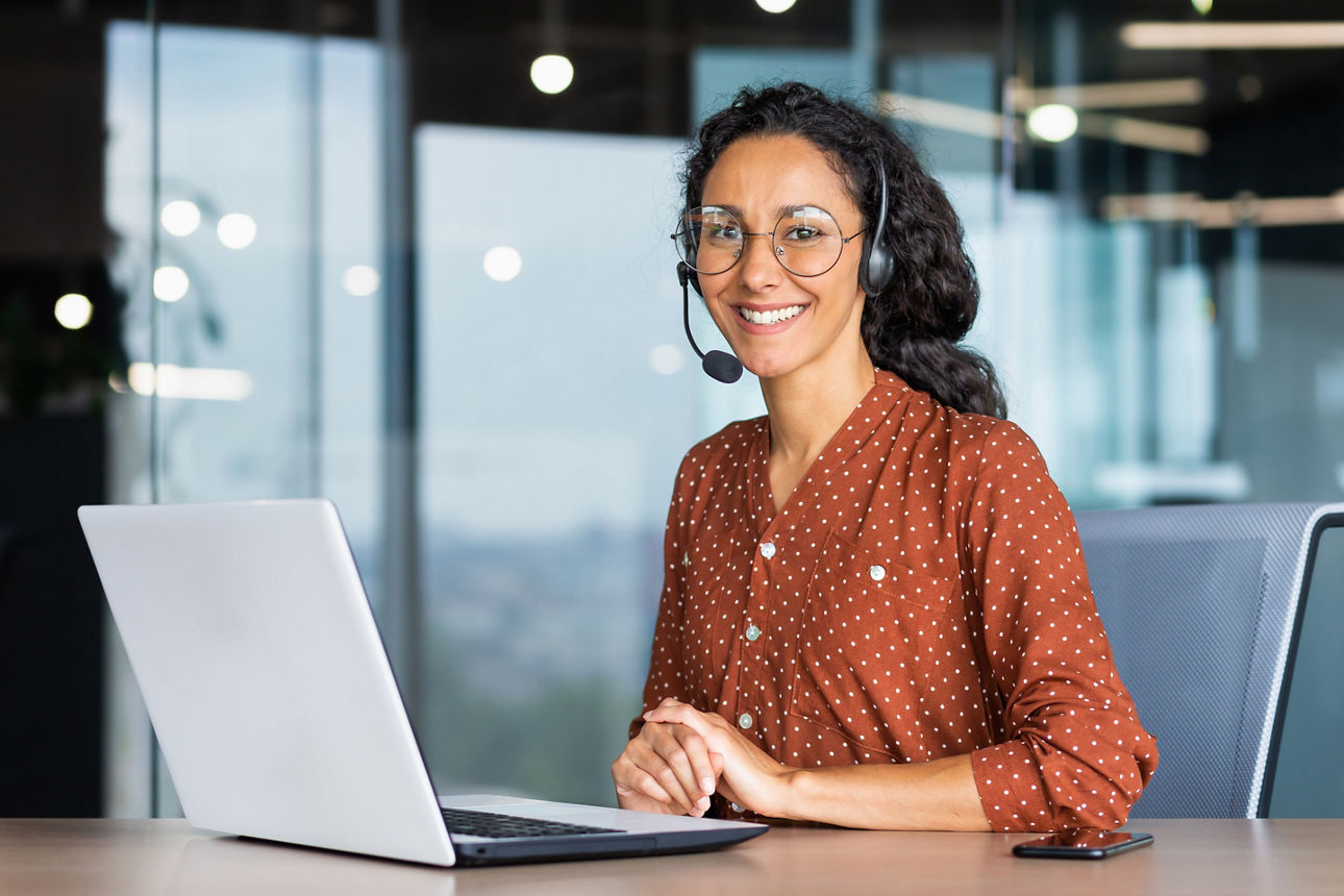 Eine Frau mit Headset sitzt am Laptop