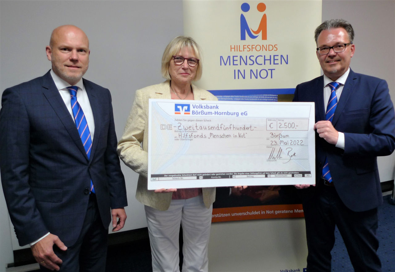 Drei Menschen die einen Spendencheck überreichen 