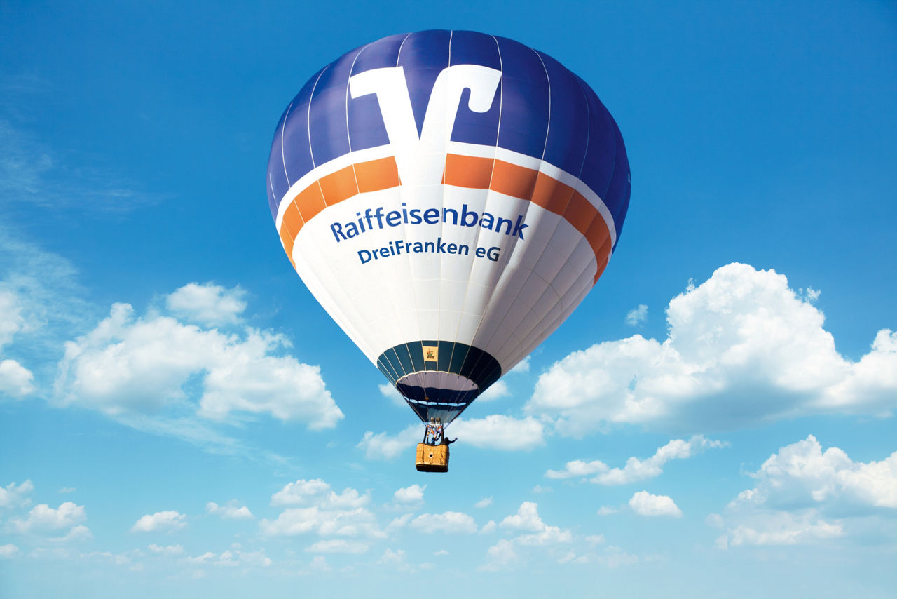 Der Heißluftballon der Bank am blauen Himmel