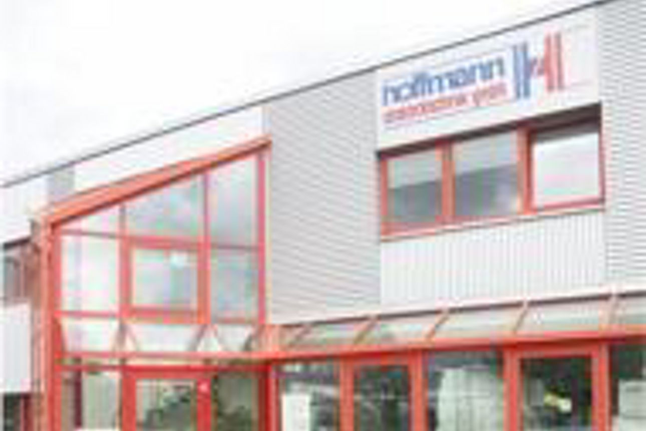 Foto der Fassade einer Fabrik mit orangefarbenen Stahlträgern