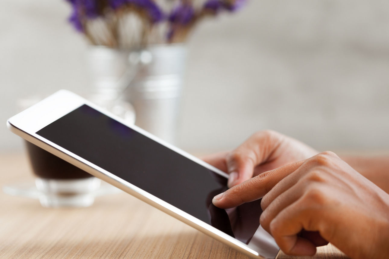 Nahaufnahme einer Hand, die ein digitales Tablet berührt.