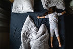 Ein Kleinkind liegt ausgebreitet im Bett