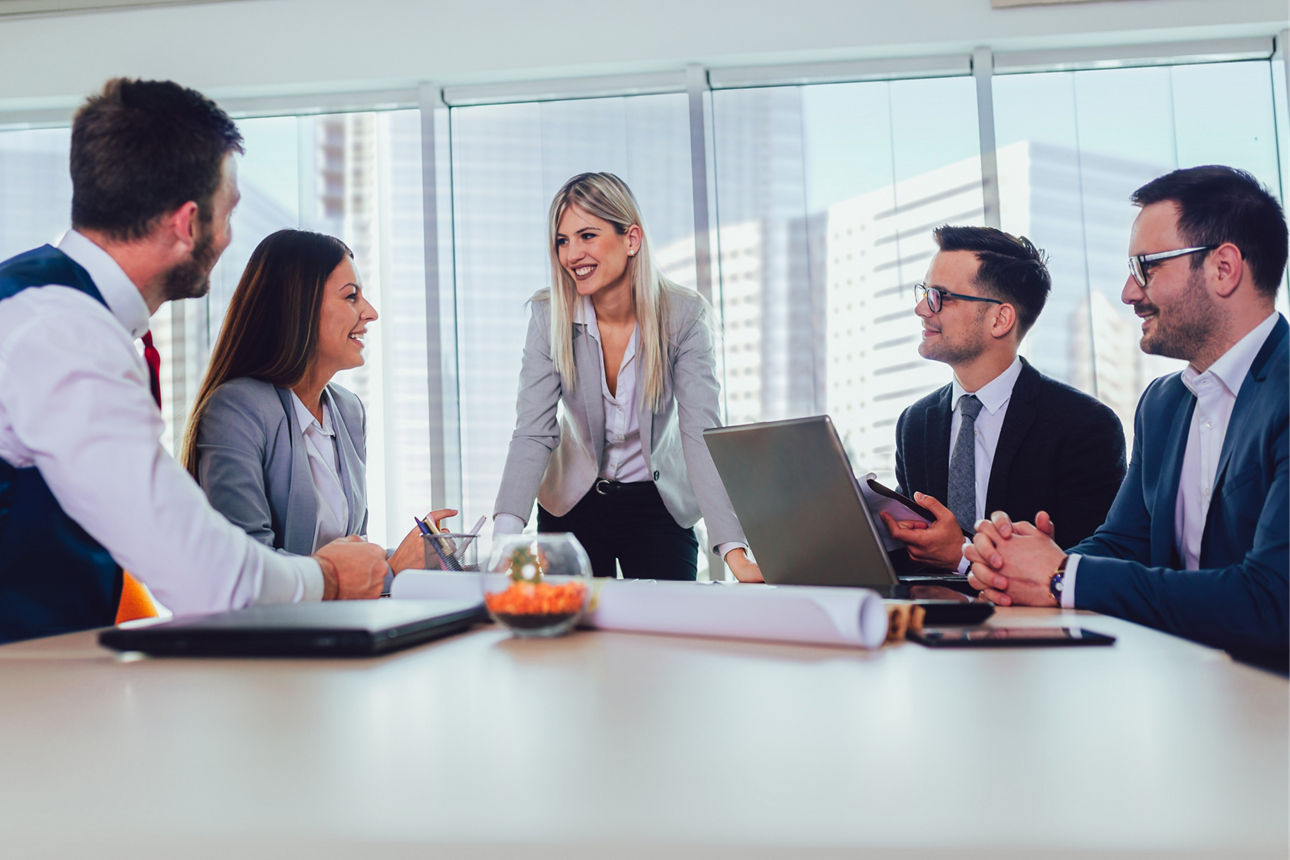 Fünf junge Geschäftsleute arbeiten an einem Tisch in einem modernen Büro, umgeben von Laptops und Notizen. 