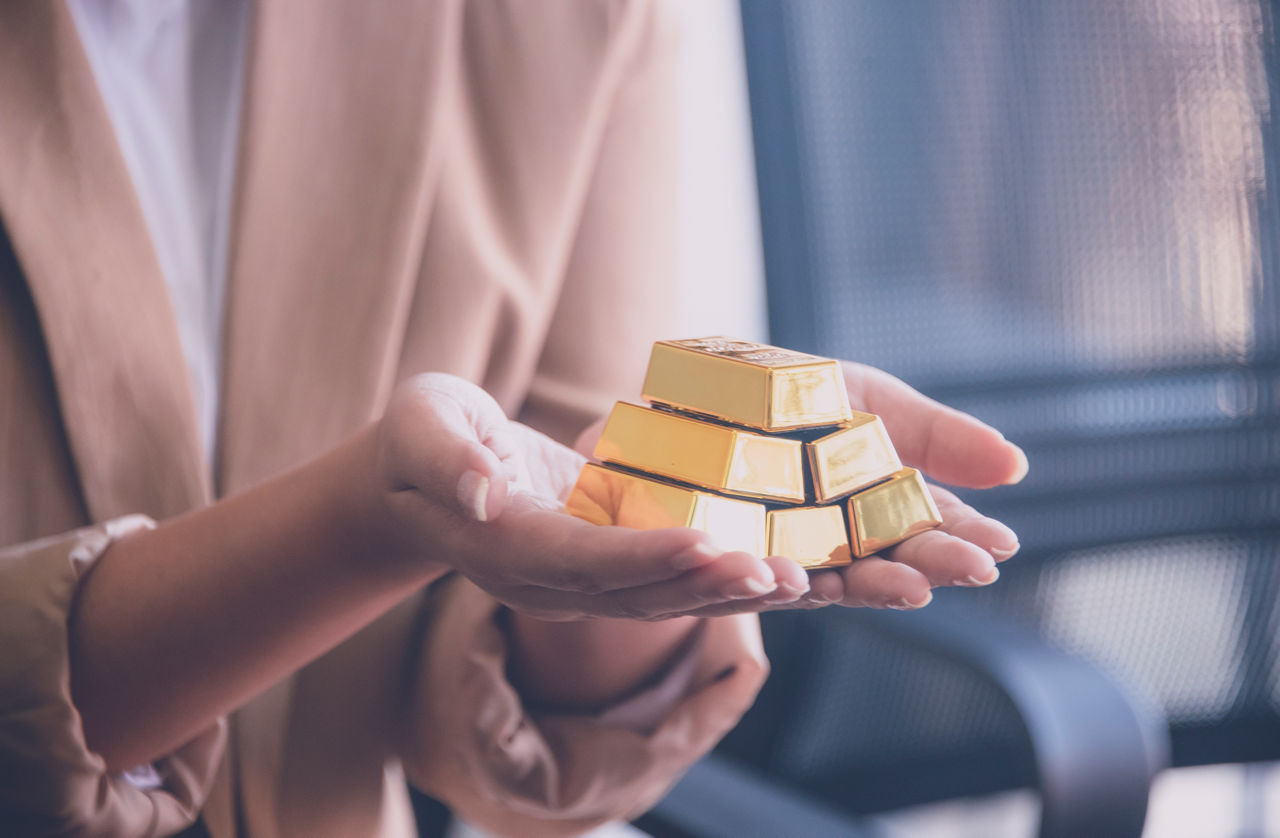 Frauenhände halten 6 kleine Goldbarren