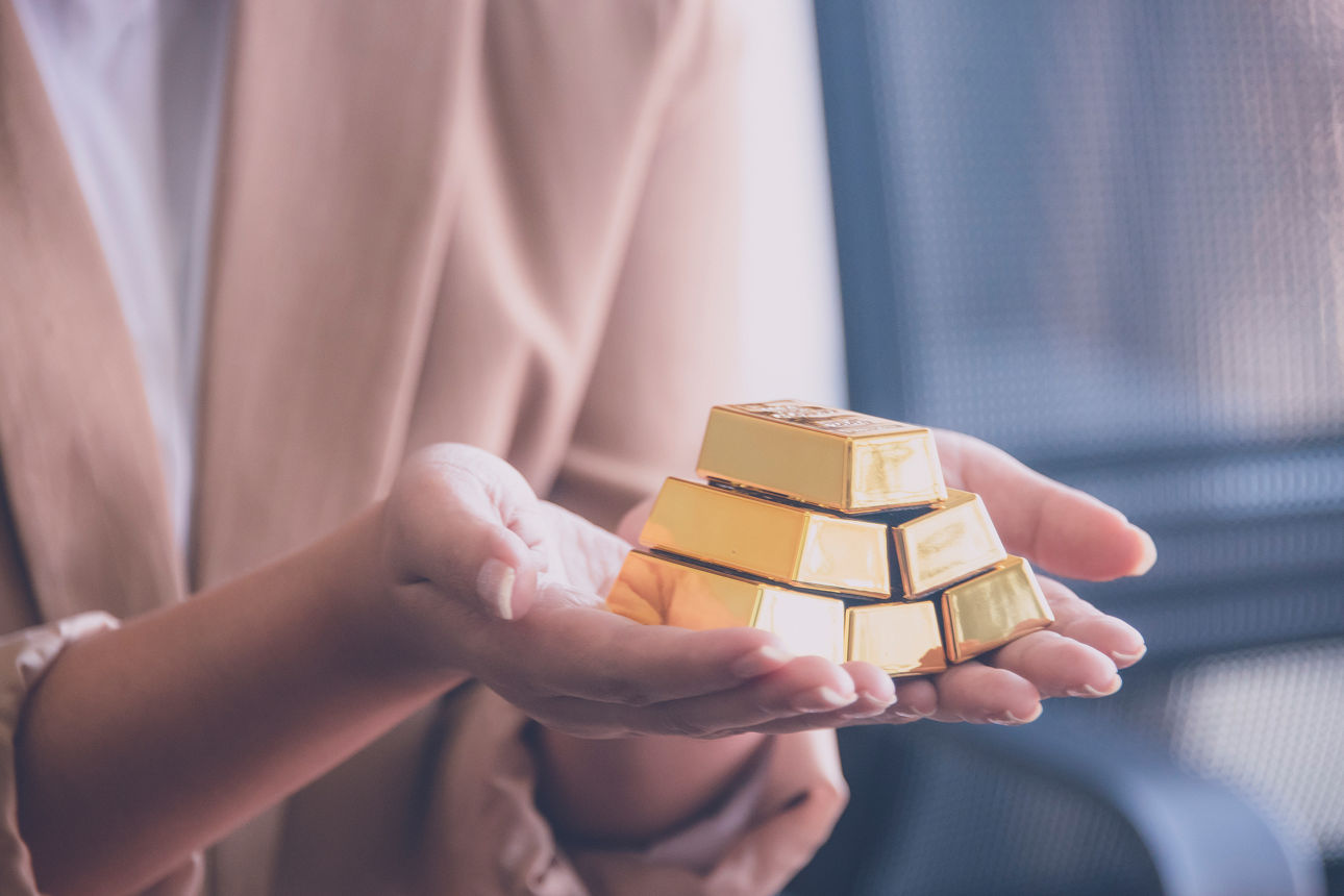 Weibliche Hände halten 6 kleine Goldbarren