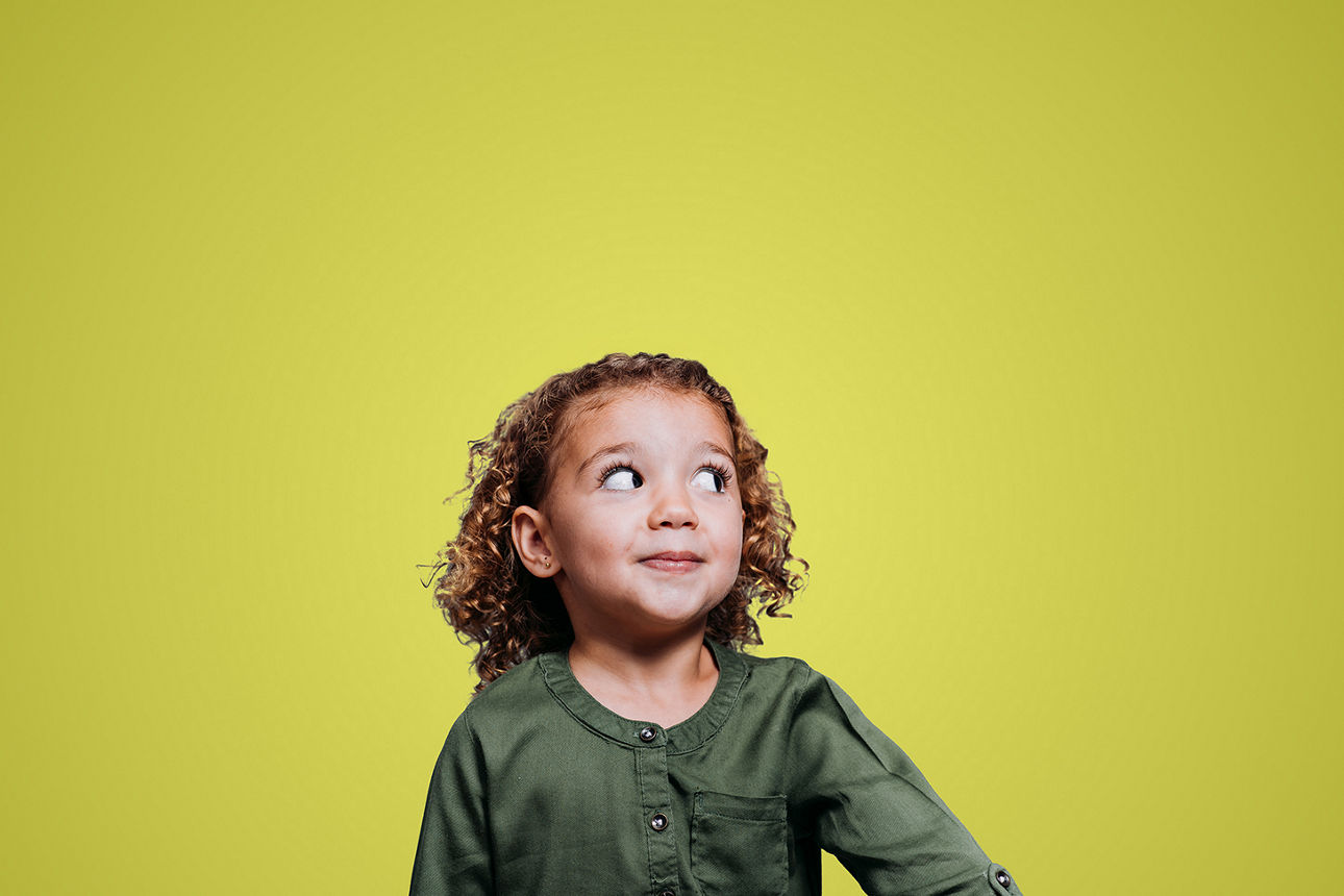 Ein kleines Mädchen mit einem kleinen Plüschgeweih auf dem Kopf guckt erwartungsvoll nach oben.