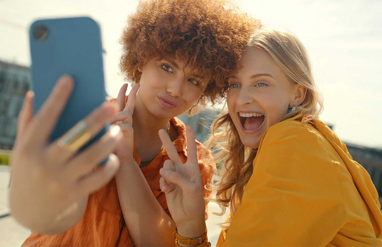 Freunde, Peace-Zeichen und Selfie-Lächeln in der Stadt für glückliche Erinnerung, Profilbild oder Social Media. V-Hand-Emoji, Comic und Mädchen oder Frauen, die lachen und Fotos machen, sich verbinden und die Zeit in der Stadt genießen.