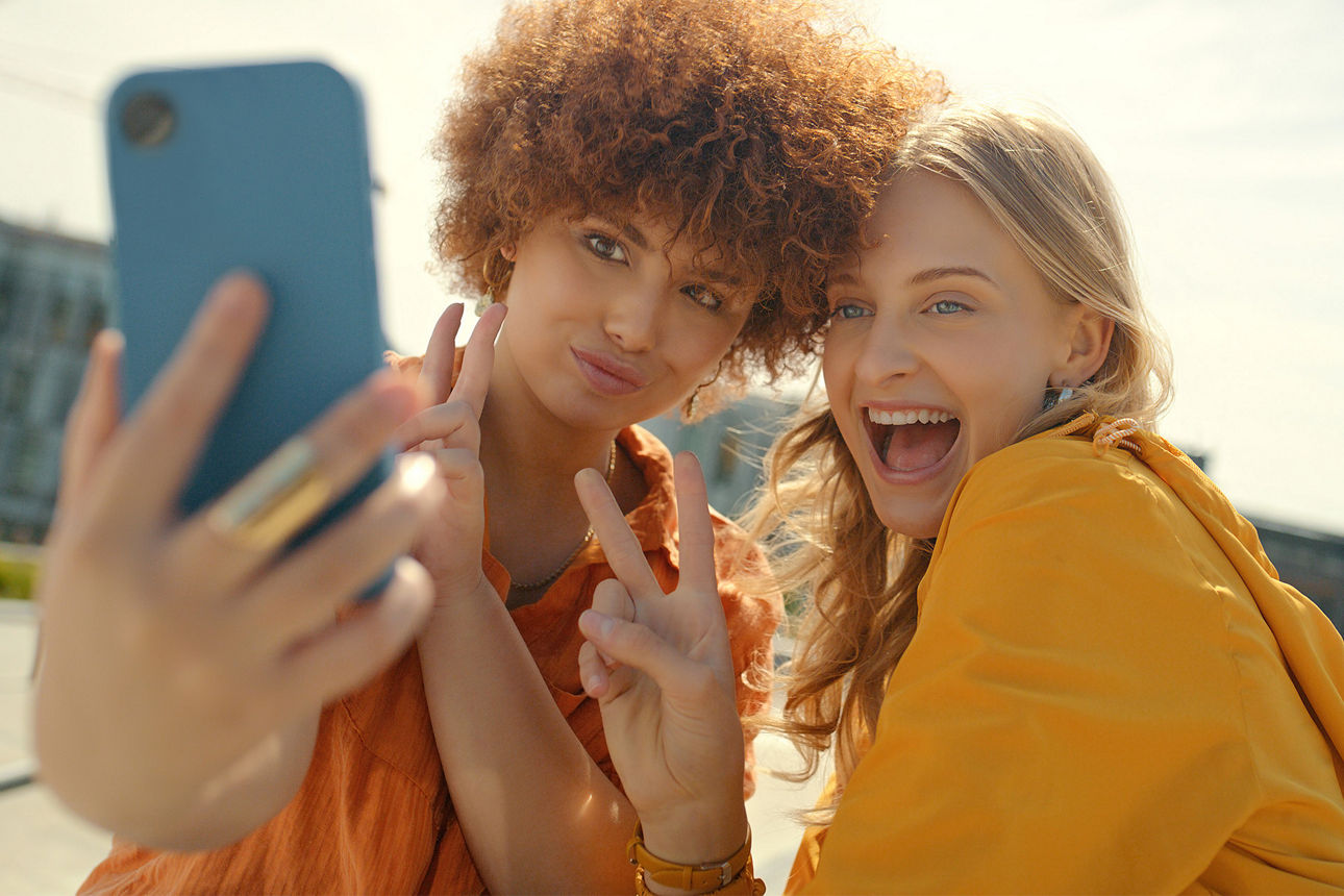 Freunde, Peace-Zeichen und Selfie-Lächeln in der Stadt für glückliche Erinnerung, Profilbild oder Social Media. V-Hand-Emoji, Comic und Mädchen oder Frauen, die lachen und Fotos machen, sich verbinden und die Zeit in der Stadt genießen.