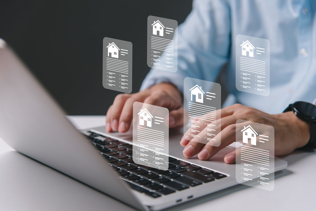 Person sitzt vor dem Laptop, visuel zu sehen sind mehrere Pop-up-Fenster die Immobilienportfolios zeigen.