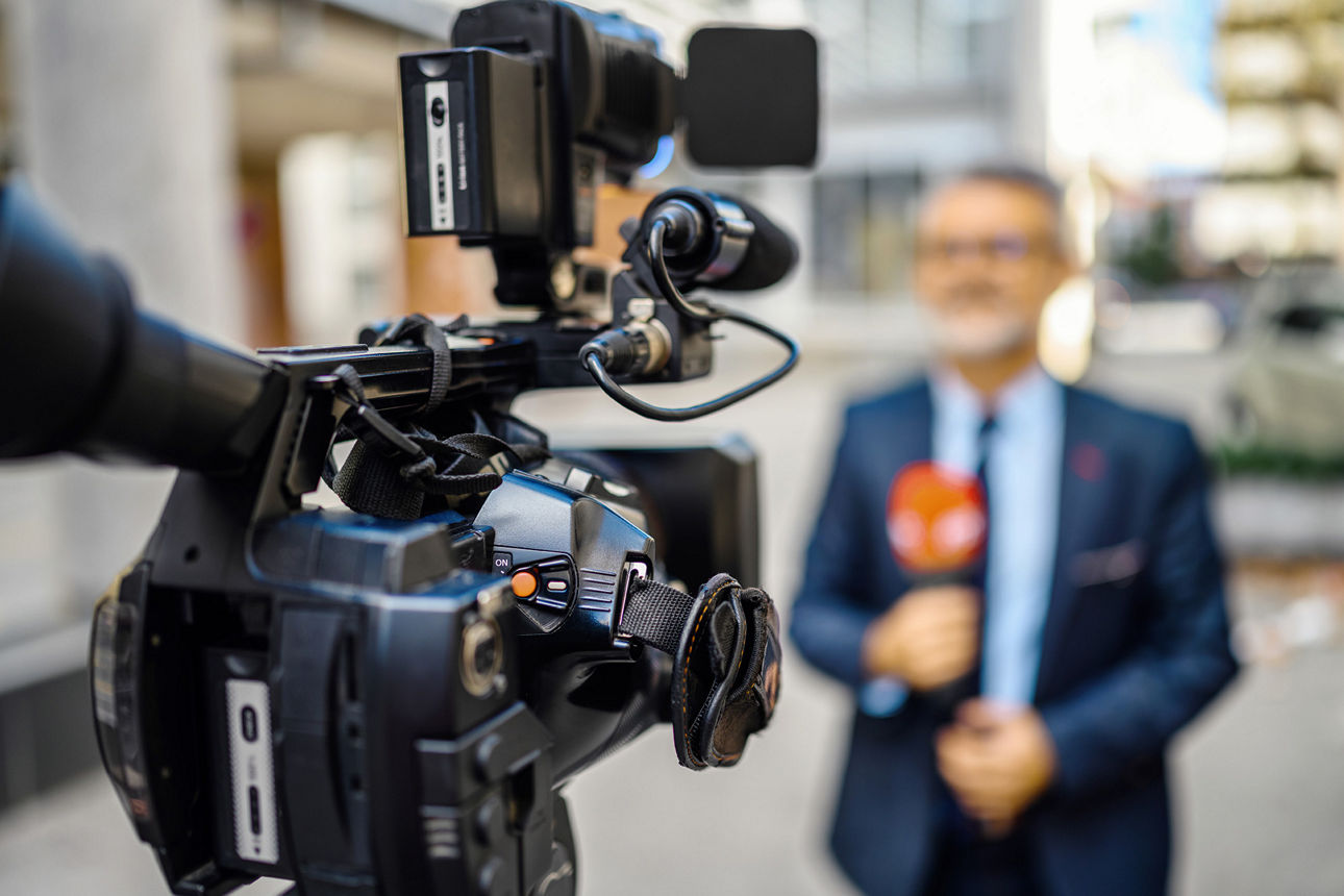 Moderator steht vor der Kamera