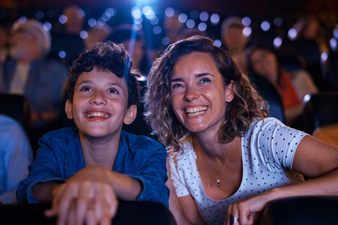Mitten in der Einstellung eines fröhlichen Jungen und seiner Mutter, die sich im Kino amüsieren