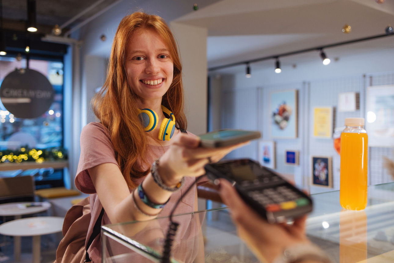 Junge Frau nutz ihr Smartphone um kontaktlos zu bezahlen