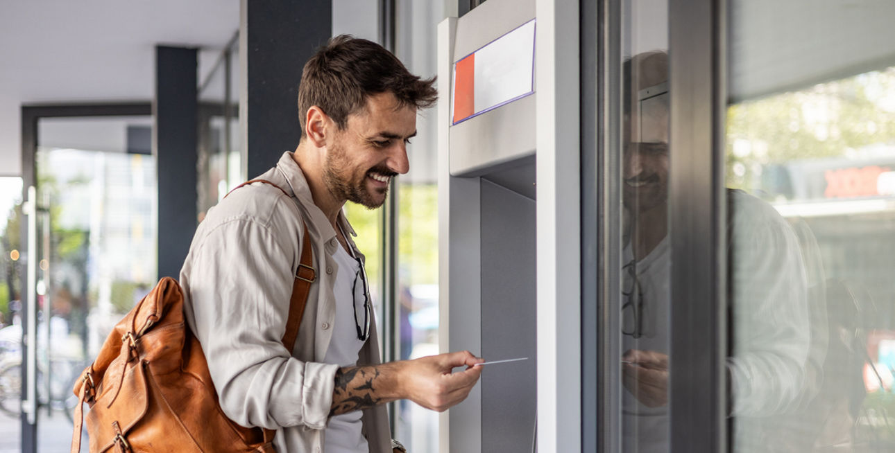 Mann hebt Geld am Geldautomaten ab