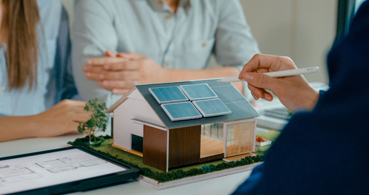 Ein Modelhaus auf einem Schreibtisch mit Solarpanelen auf dem Dach.