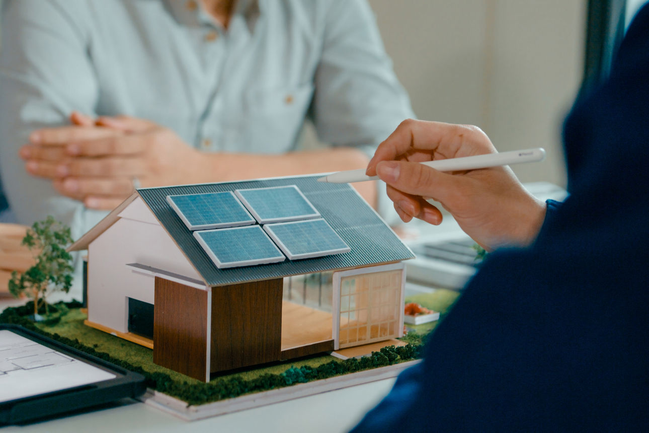 Ein Modelhaus auf einem Schreibtisch mit Solarpanelen auf dem Dach.