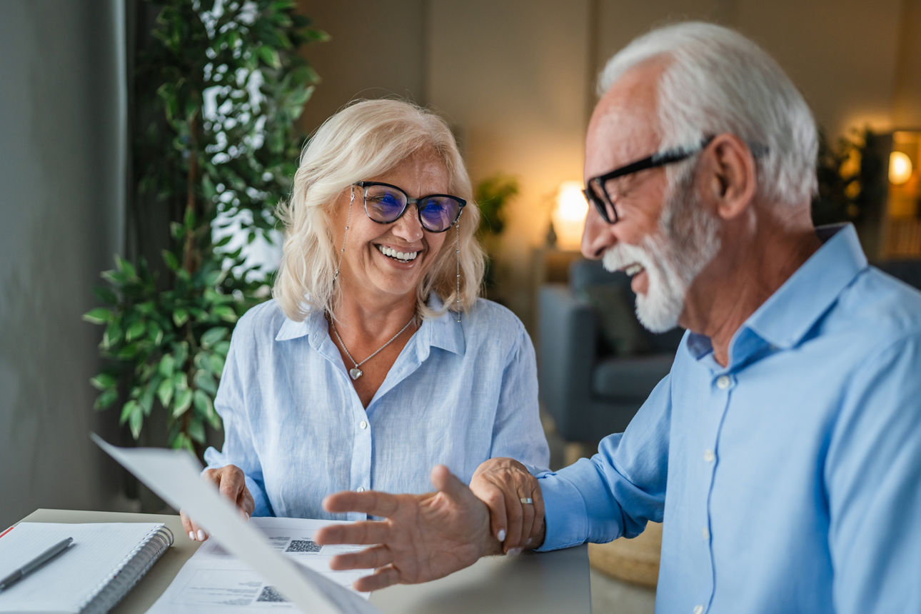 Ein älteres Paar am Tisch schaut auf Dokumente
