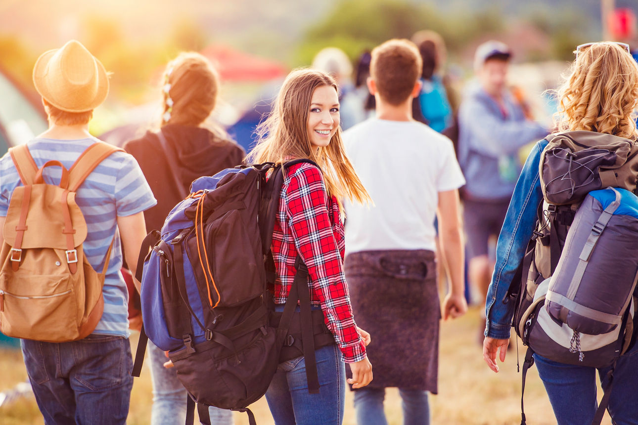 Mädchen in Gruppe von Schülern blickt zurück und lächelt, sie trägt einen Rucksack