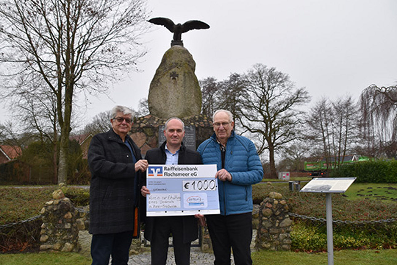 Eine bedeutende Spende wird für einen guten Zweck überreicht, wobei sich die Personen im Freien versammelt haben.