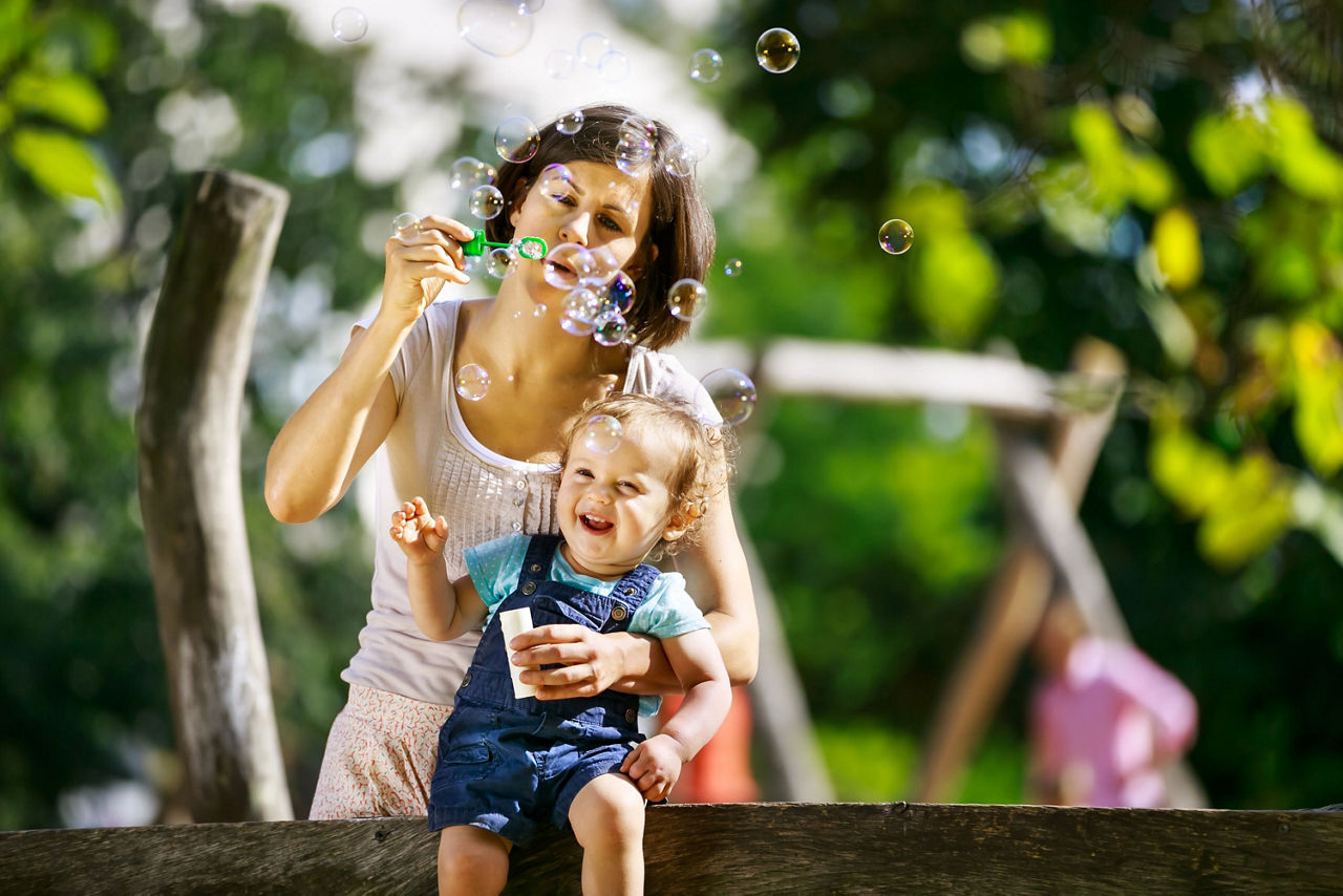 Mutter und Kind machen Seifenblasen im Park