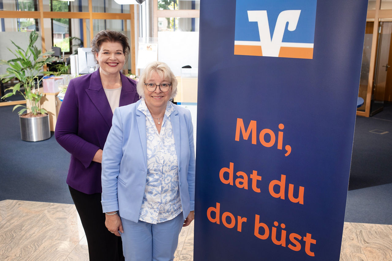 Zwei Frauen stehen neben einem Volksbank-Banner mit der Aufschrift "Moi, dat du dor büst".