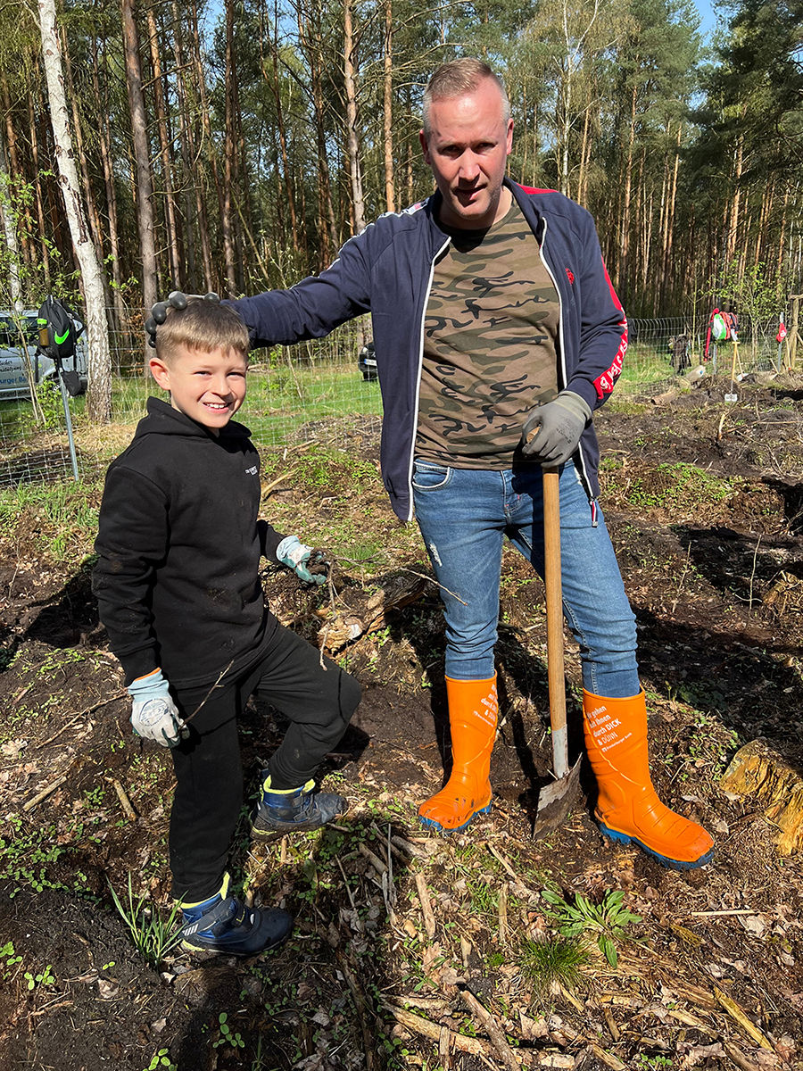 Mann in orangenen Gummistiefeln und Junge im Wald