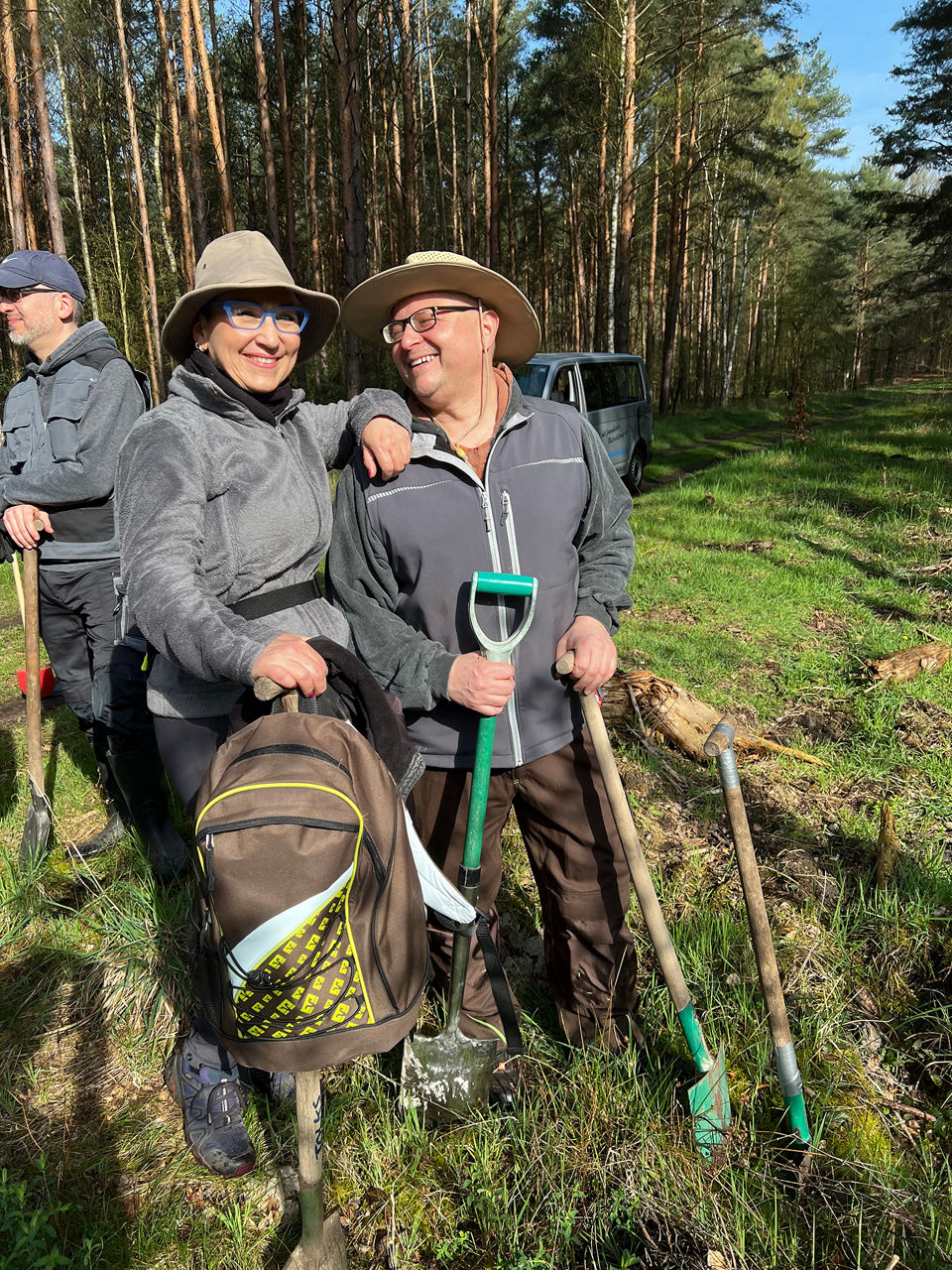 Zwei Lachende Personen mit Spaten in der Hand im Wald