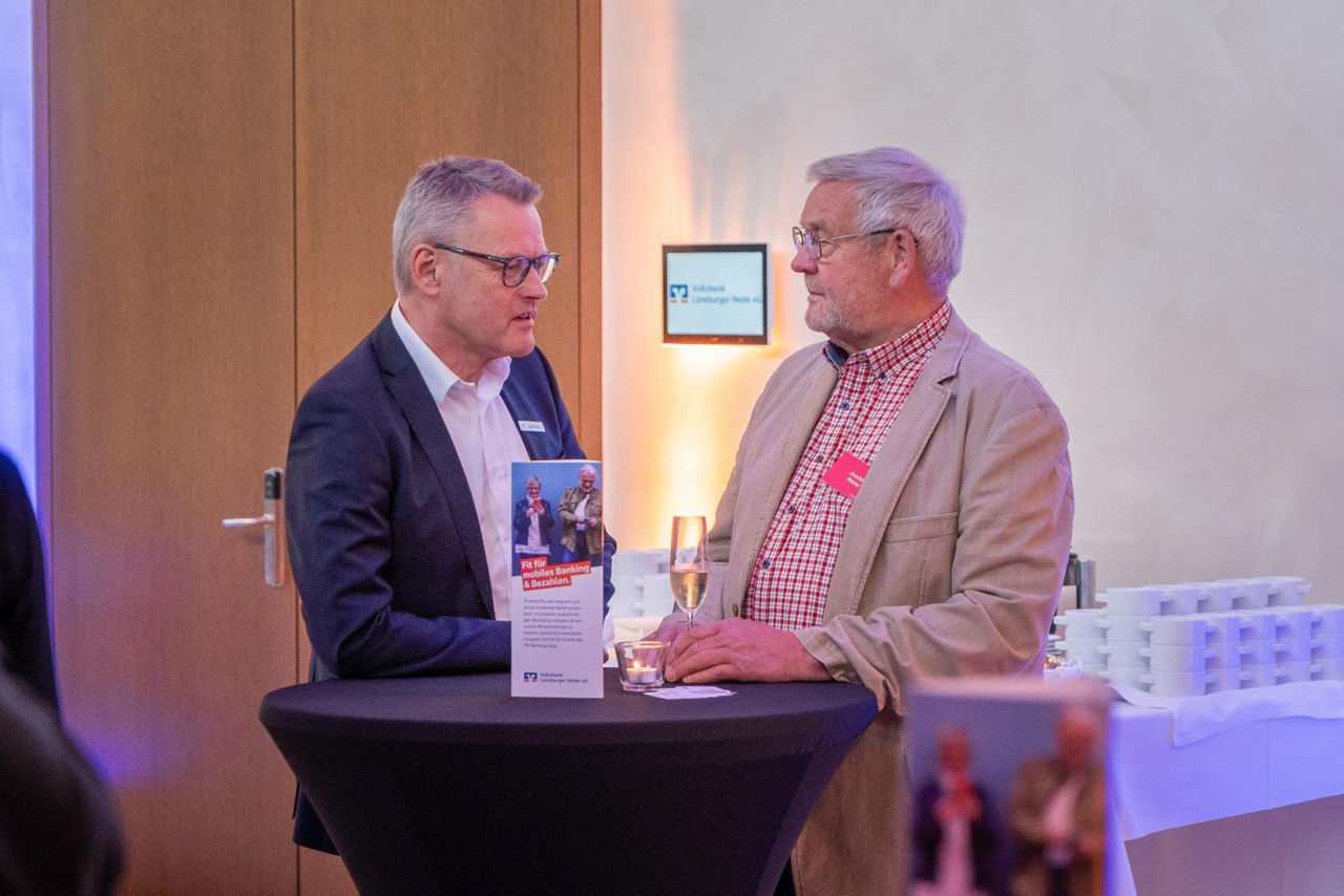 zwei Männlich gelesene Vertreter im Gespräch im Foyer an einem Stehtisch