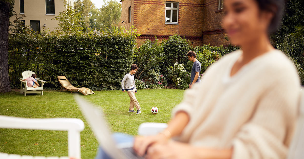 Frau sitzt im Laptop im Garten