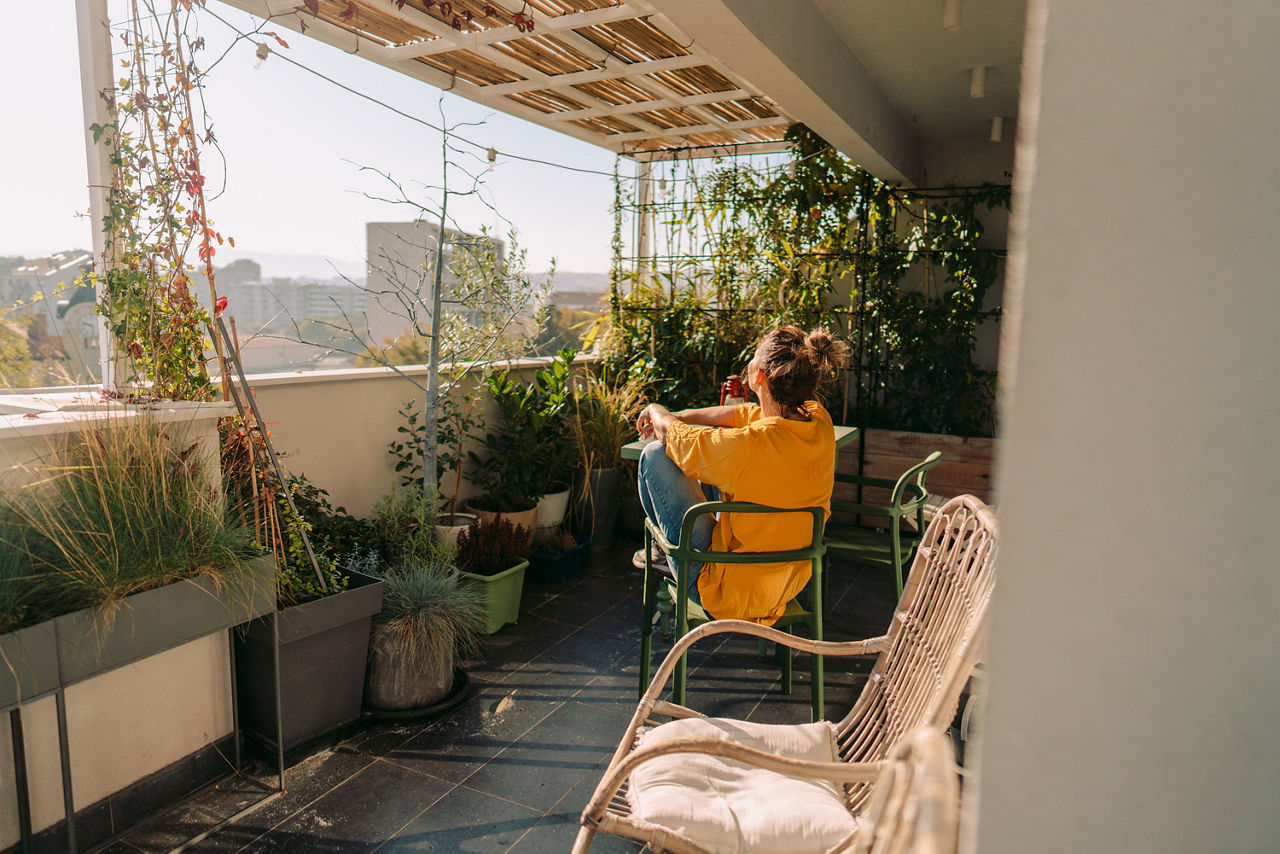 Eine Frau sitzt auf einem Balkon und genießt die Sonne.