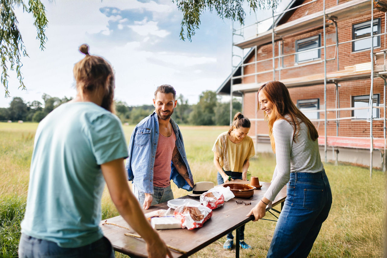 Freunde grillen vor ihrem neu finanzierten und gebauten Haus