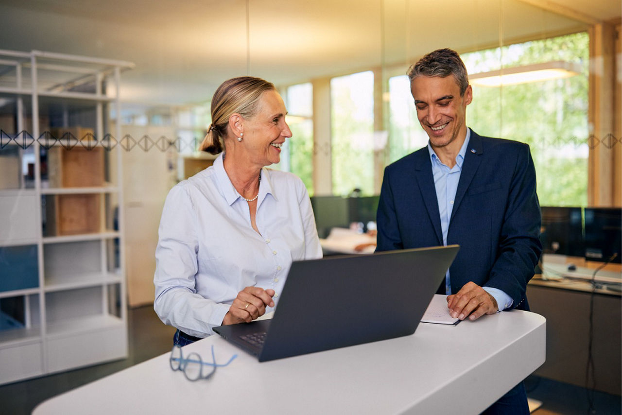 Kunde und Beraterin geben am Notebook einen Immobiliensuchauftrag ein.