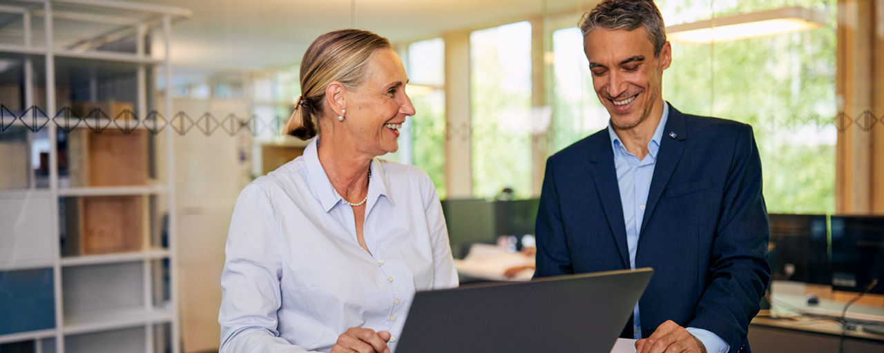 Kunde und Beraterin geben am Notebook einen Immobiliensuchauftrag ein.