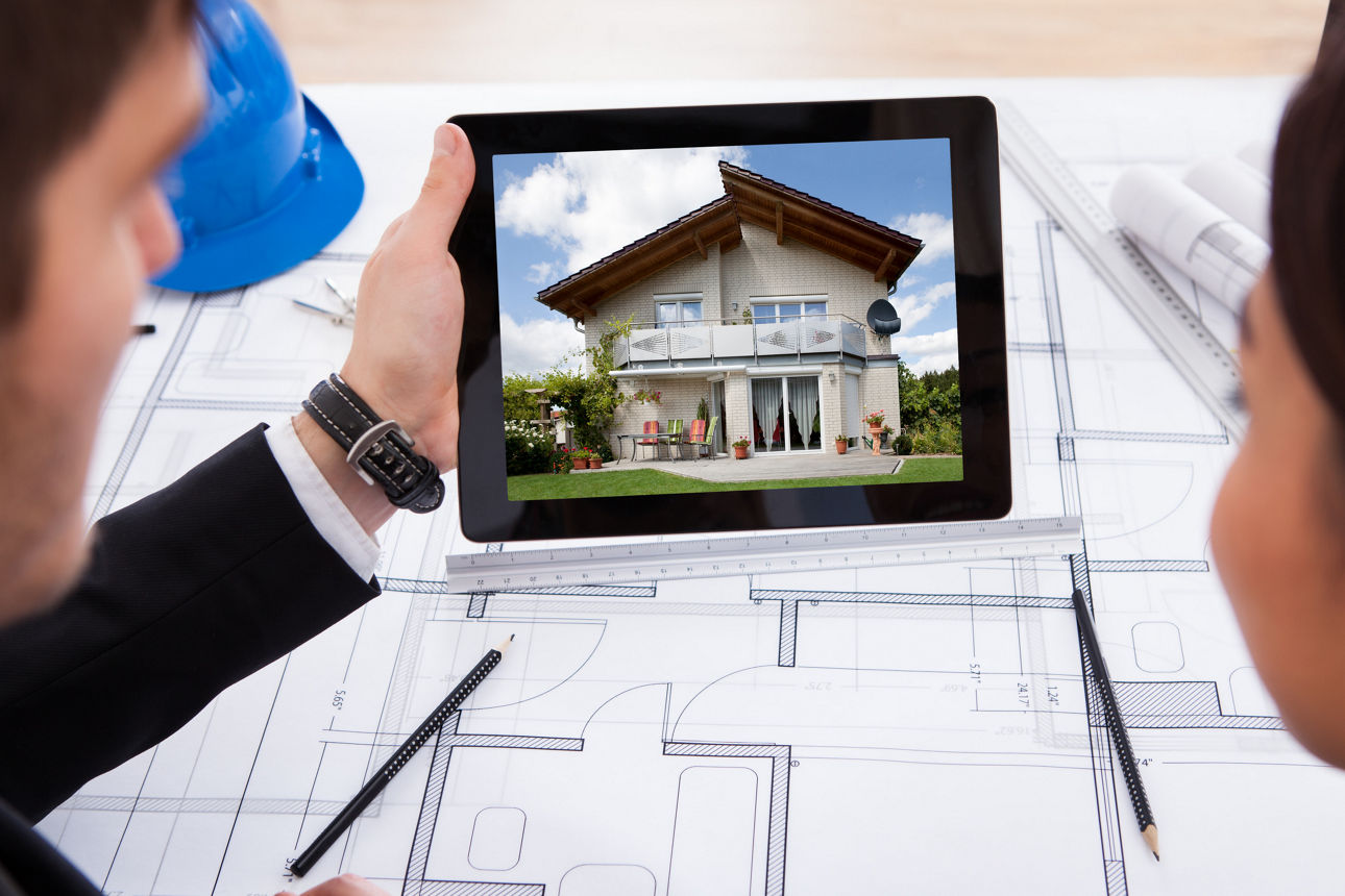 2 Personen betrachten einen Rahmen, der ein Haus bildet