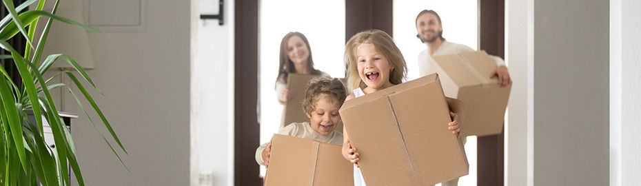 Familie mit zwei Kindern, die Kinder haben Kartons in der Hand und freuen sich