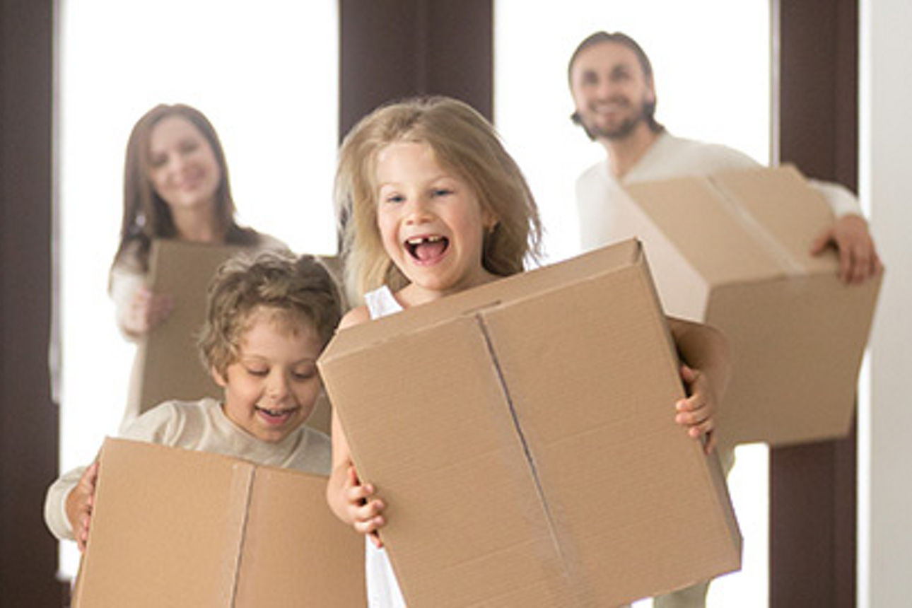 Familie mit zwei Kindern, die Kinder haben Kartons in der Hand und freuen sich