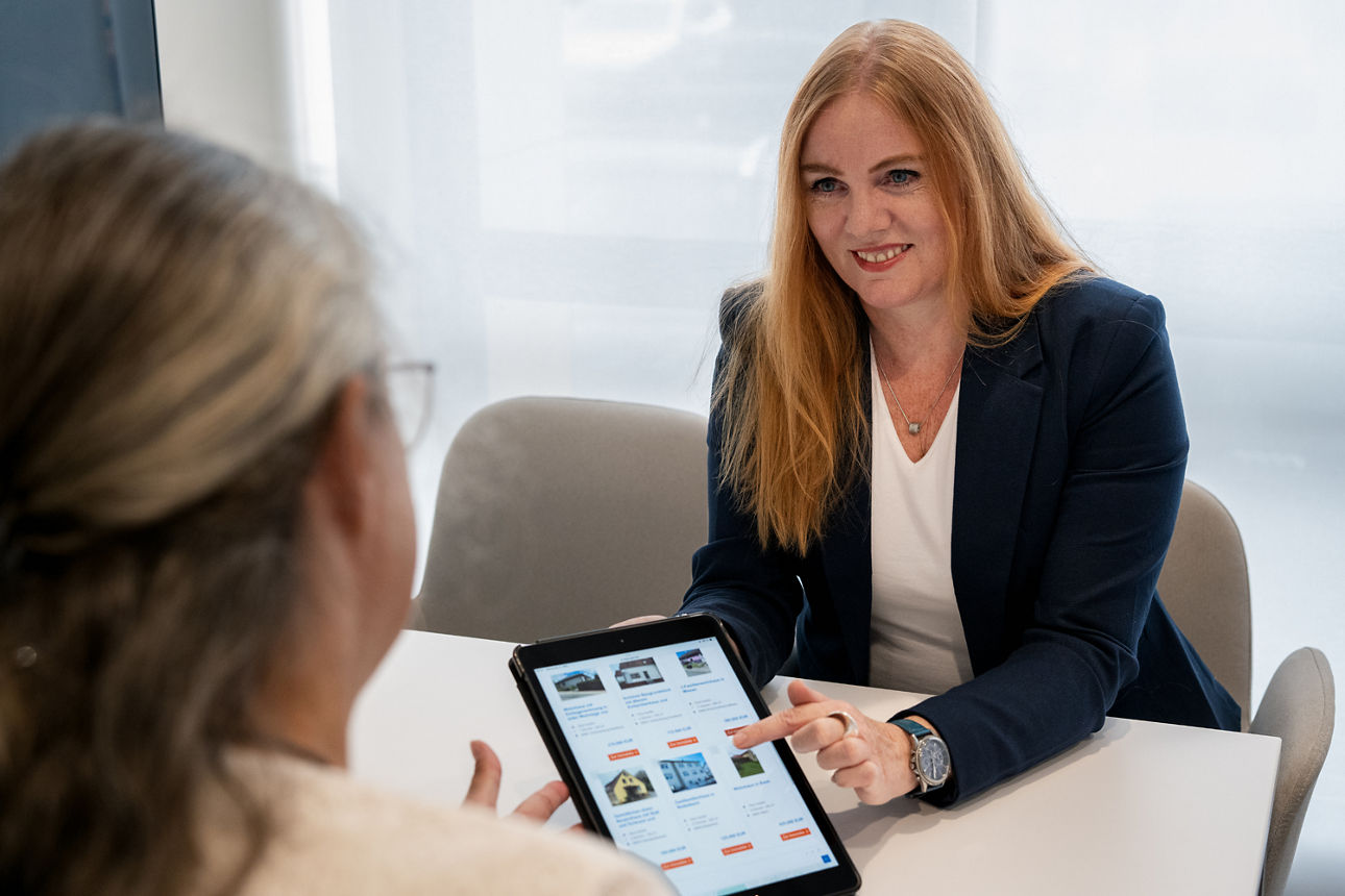 Eine Immobilien Maklerin zeigt einer Kundin ein Tablet