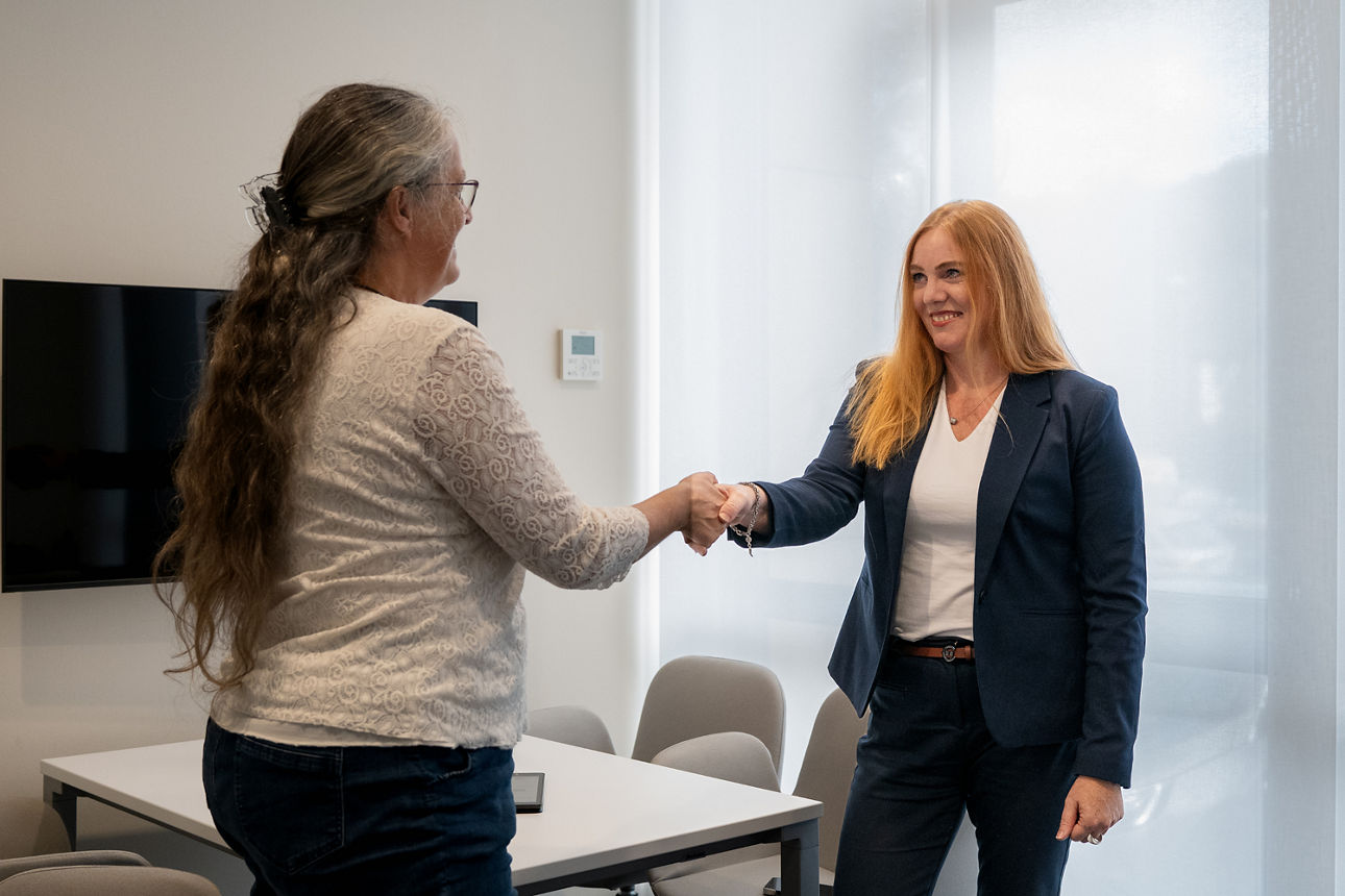 Eine Immobilienmaklerin schüttelt einer Kundin die Hand