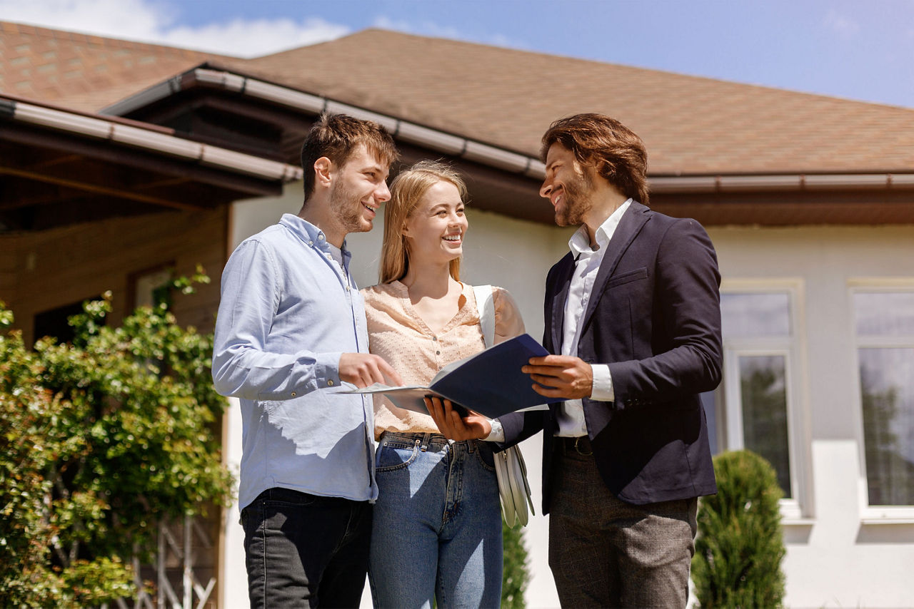 Immobilienmakler, der seinen Kunden im Hinterhof des Hauses den Miet- oder Kaufvertrag zeigt
