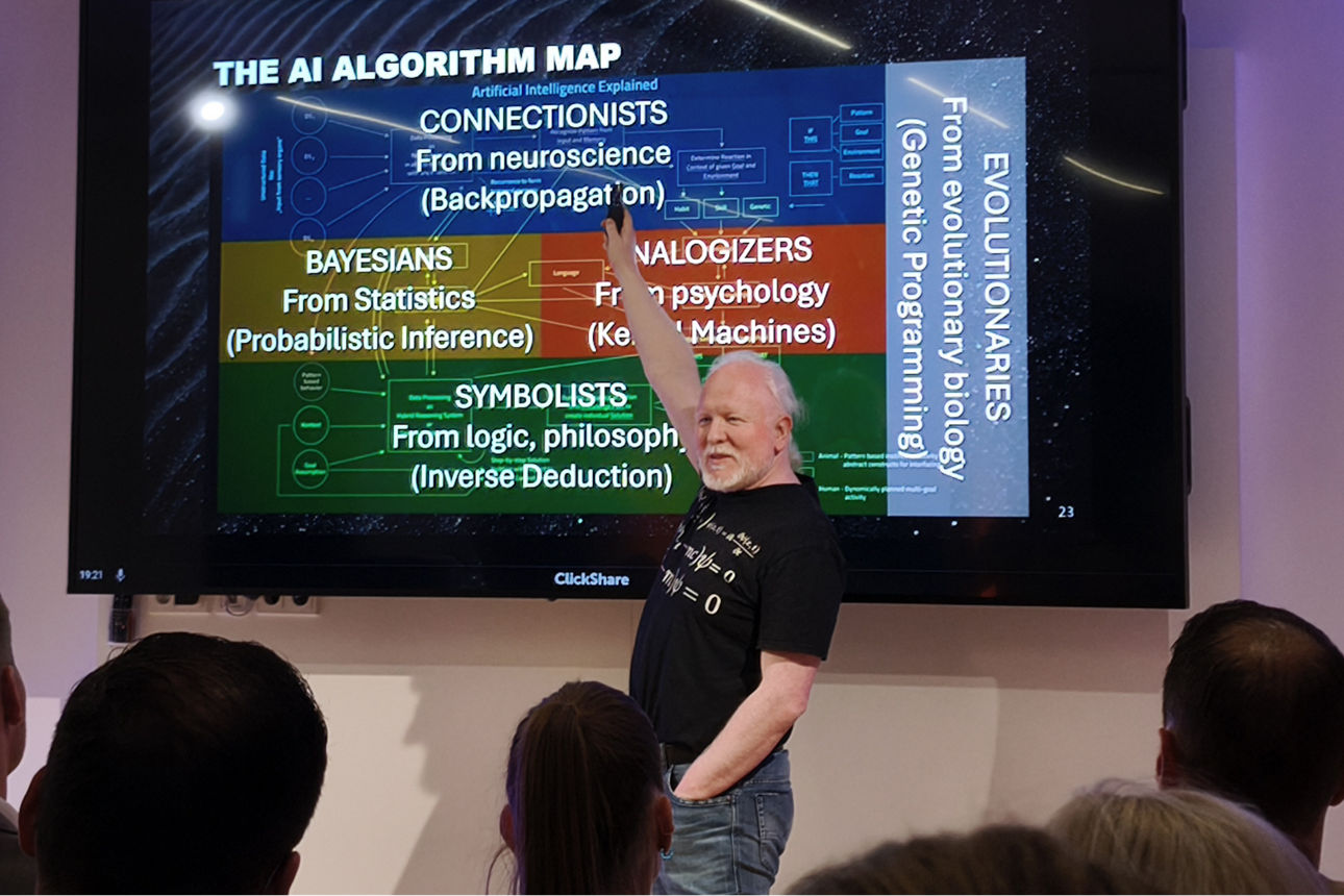 Chris Boos steht vor einem großen Monitor und zeigt auf diesen