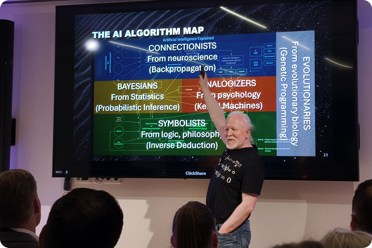 Chris Boos steht vor einem großen Monitor und zeigt auf diesen