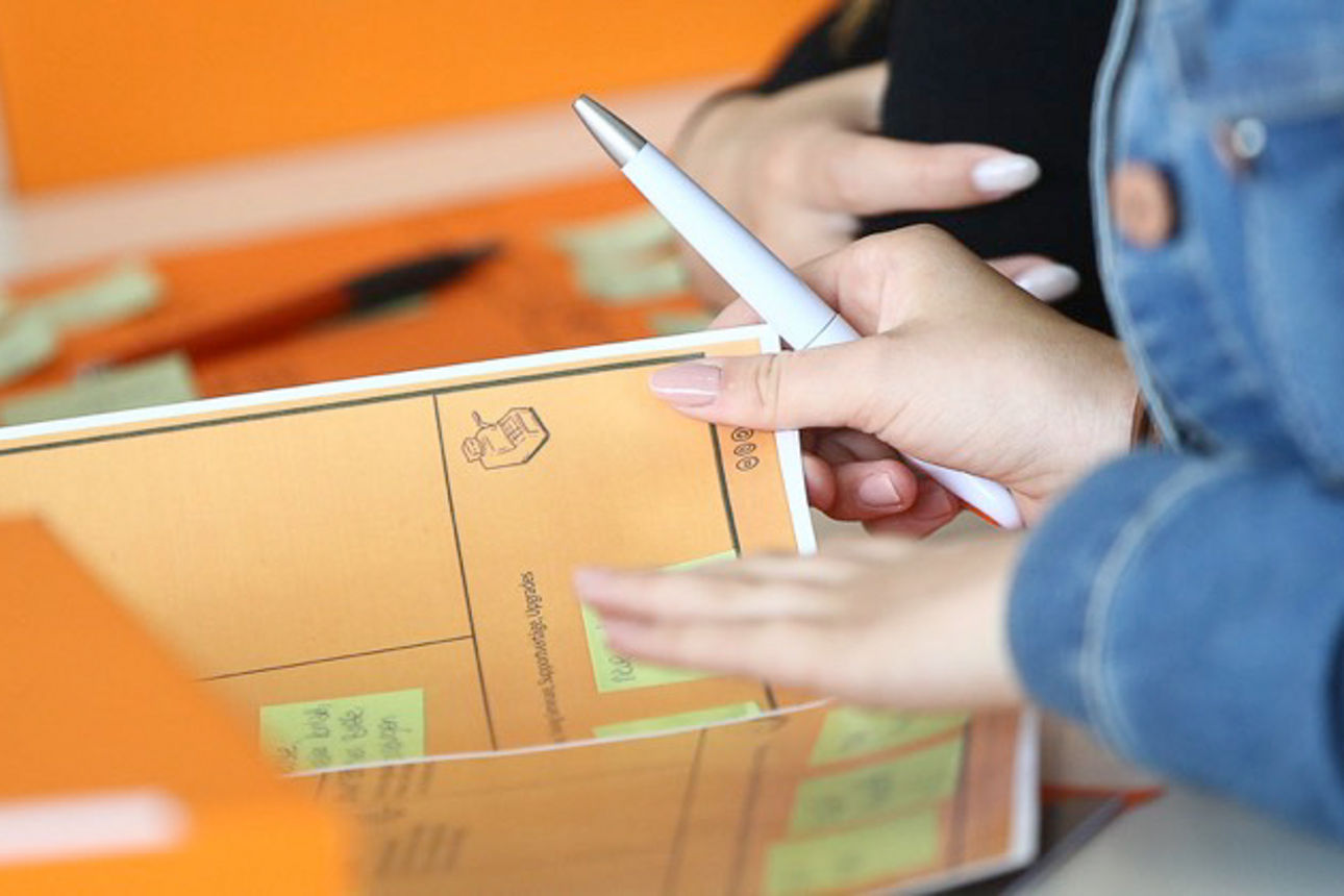 Eine Person füllt ein Formular aus umgeben von orangenen Innovationskickboxen