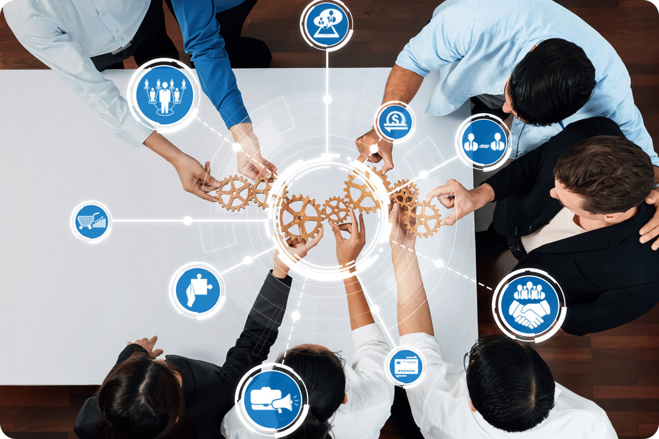 Eine Gruppe von Menschen hält ineinander greifende Zahnräder zusammen