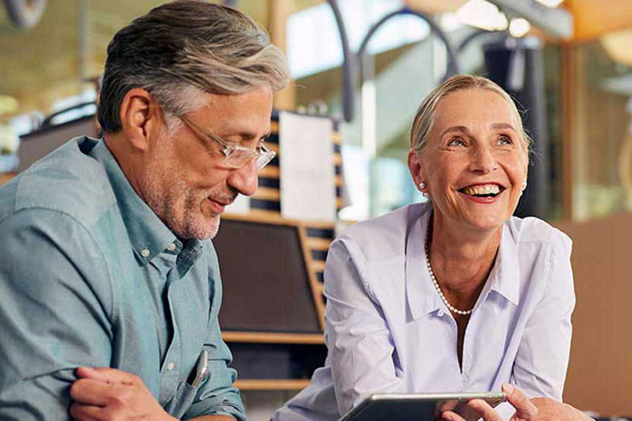 Kreditprogramme, Zuschüsse und Sicherheiten - Mann guckt auf dem Laptop und Frau lächelt
