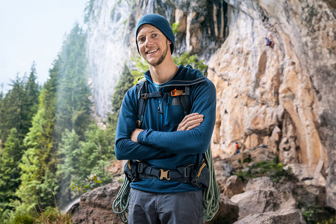Bergführer Thomas März steht in Wanderausrüstung vor einem Gebirge.