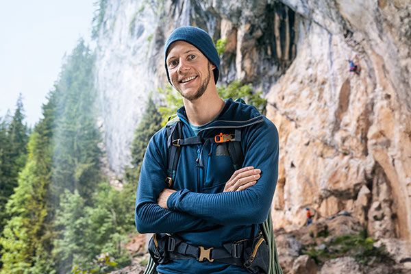 Ein Mann mit Kletterausrüstung steht vor einer Steilwand.
