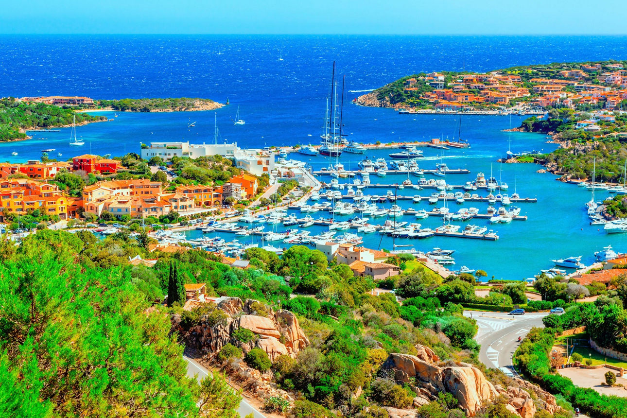Türkisblaues Meer, eine malerische Bucht und farbenfrohe Häuser an der sardinischen Küste.