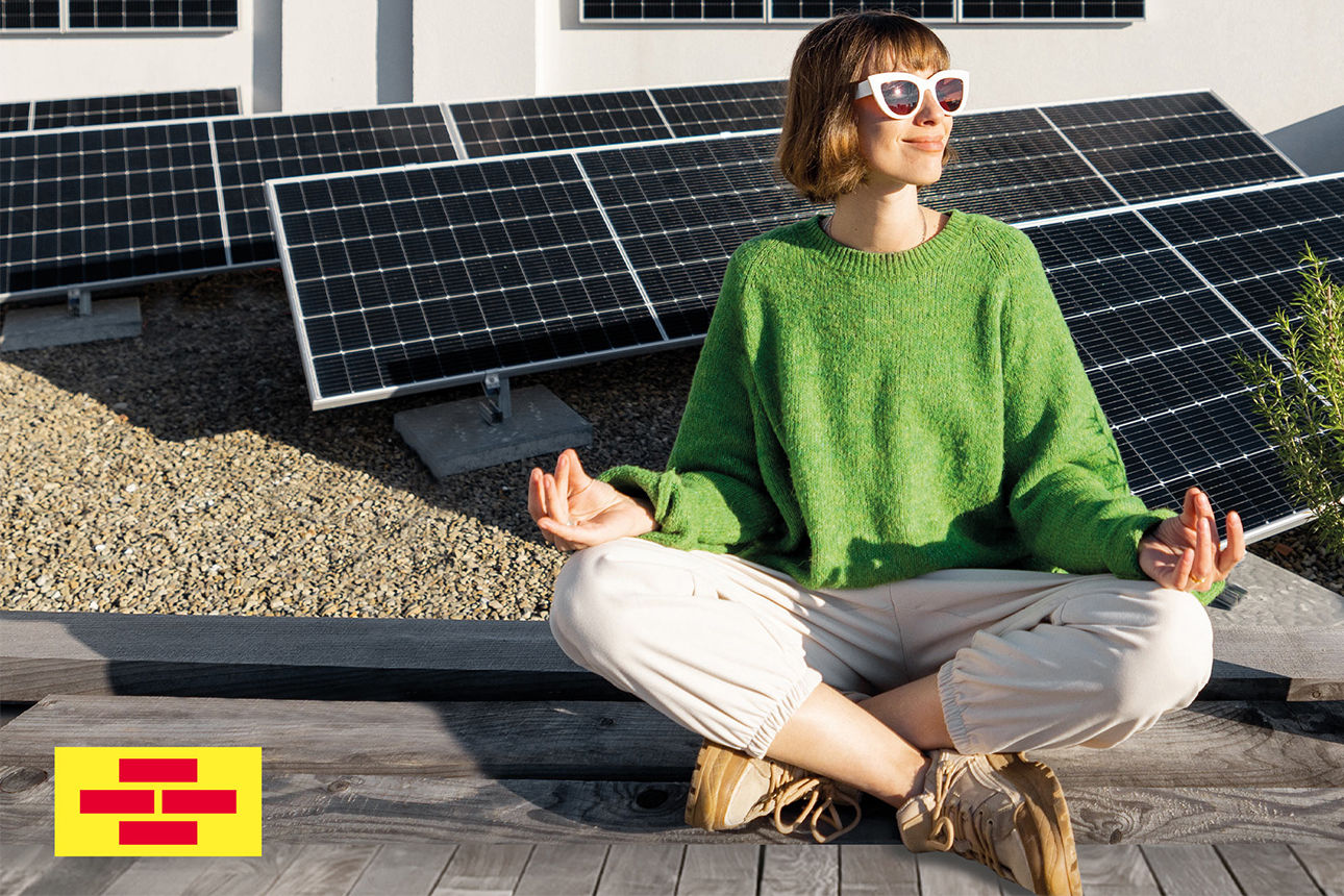 Frau sitzt im Schneidersitz vor Solaranlage