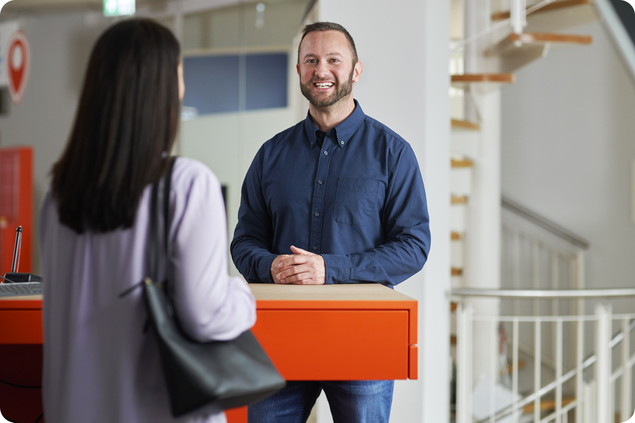 Mann und Frau stehen an einem Schreibtisch gegenüber und sind im Gespräch